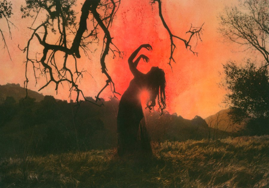 Fotografía artística. Una mujer de espaldas, reclinada, con los brazos alzados y vueltos hacia sí. El horizonte es un atardecer rojizo.